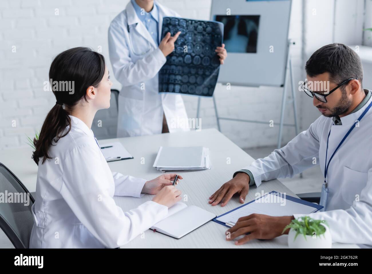 doctor pointing at brain mri scan near colleagues working with