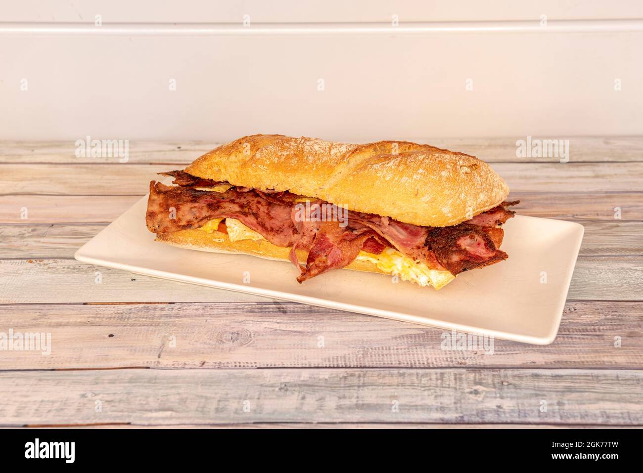 Great sandwich of French omelette and a lot of fried bacon inside a loaf of ciabatta bread in the purest Spanish style Stock Photo