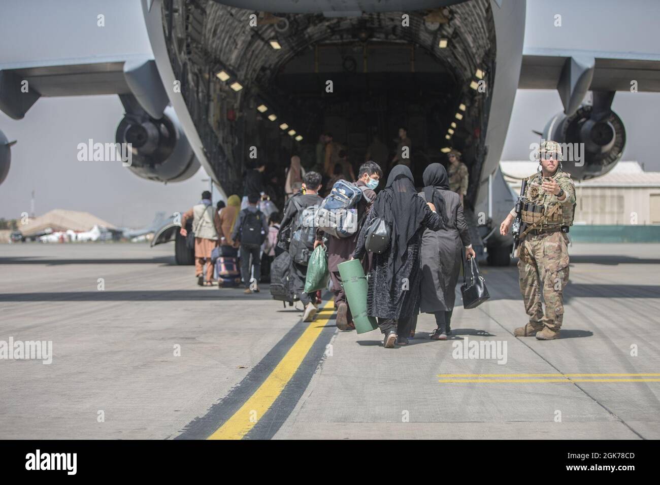 Families begin to board a U.S. Air Force Boeing C-17 Globemaster III during an evacuation at Hamid Karzai International Airport, Kabul, Afghanistan, Aug. 23. U.S. service members are assisting the Department of State with an orderly drawdown of designated personnel in Afghanistan. Stock Photo