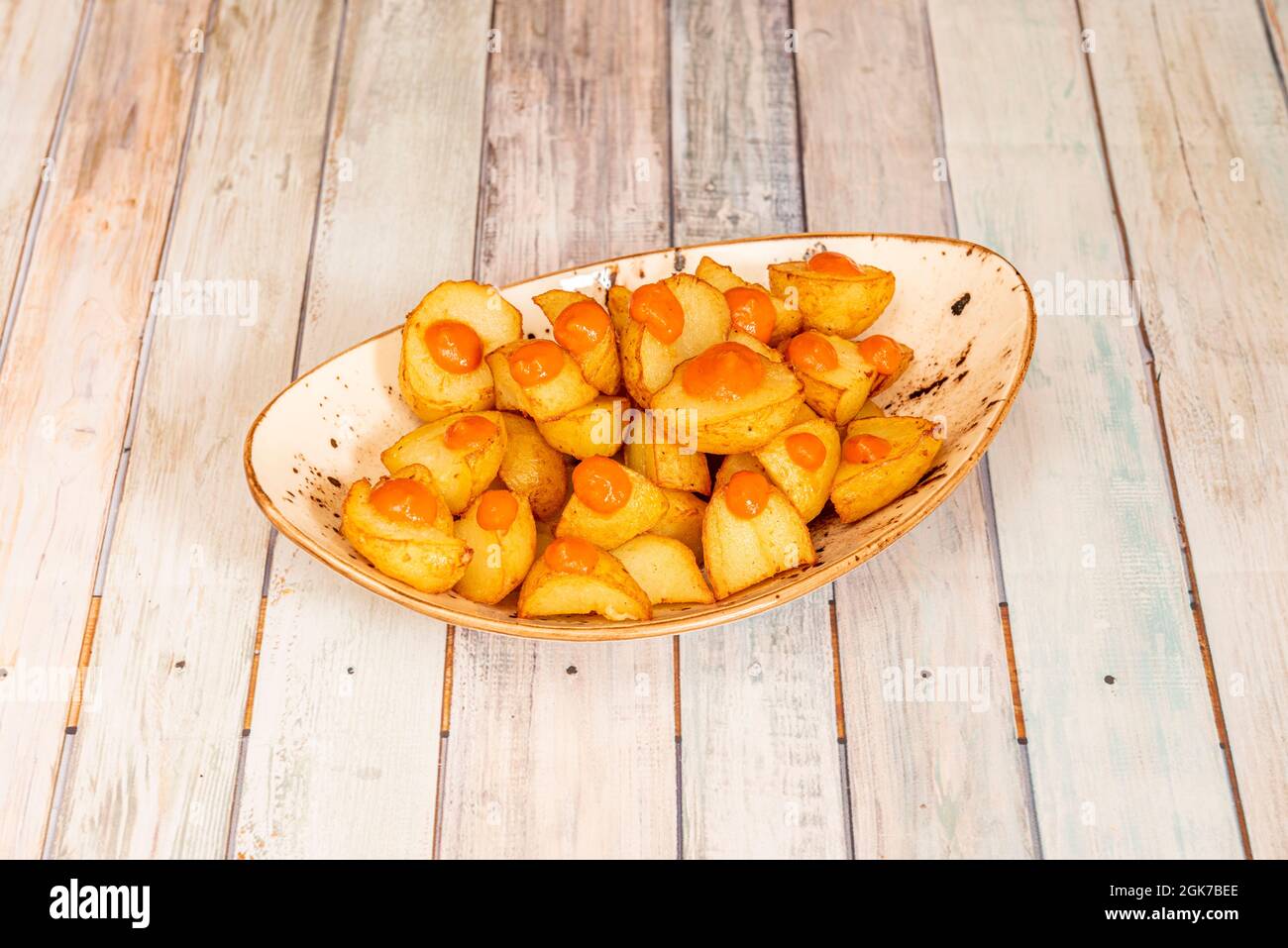 Popular Spanish tapa of hot sauce patatas bravas served in a white bowl