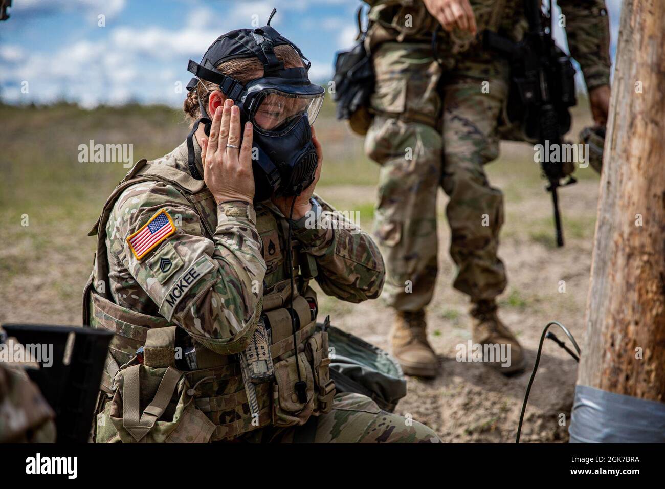 U.S. Army National Guard Staff Sgt. Taryn Mckee with 3rd Battalion, 161st Infantry Regiment, ensures proper seal on her gas mask after a simulated chemical gas attack during demolition range training at Bemowo Piskie Training Area, Poland, August 25, 2021. The demolition training was held to ensure technique and placement of explosives on objects for successful countermobility of the enemy. Training consisted of simulations of real-life scenarios and instruction. Stock Photo