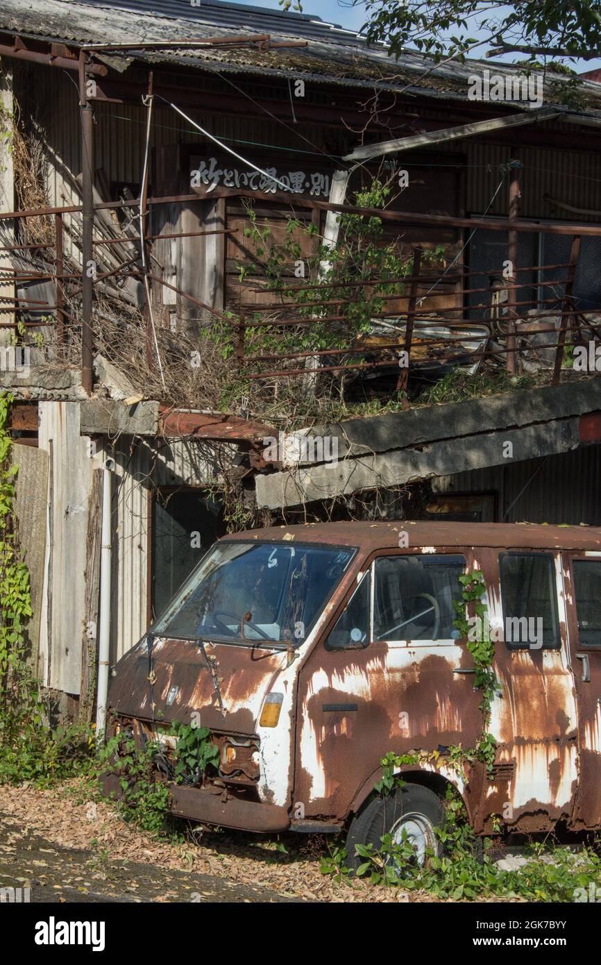 A rusty disused campervan in front of a derelict house, Beppu, Oita Prefecture, Japan, Stock Photo
