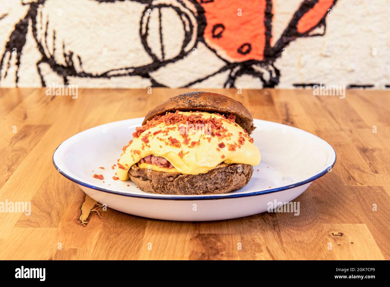 Beef burger with lots of melted cheese and crispy onion with rye bread on wooden table Stock Photo