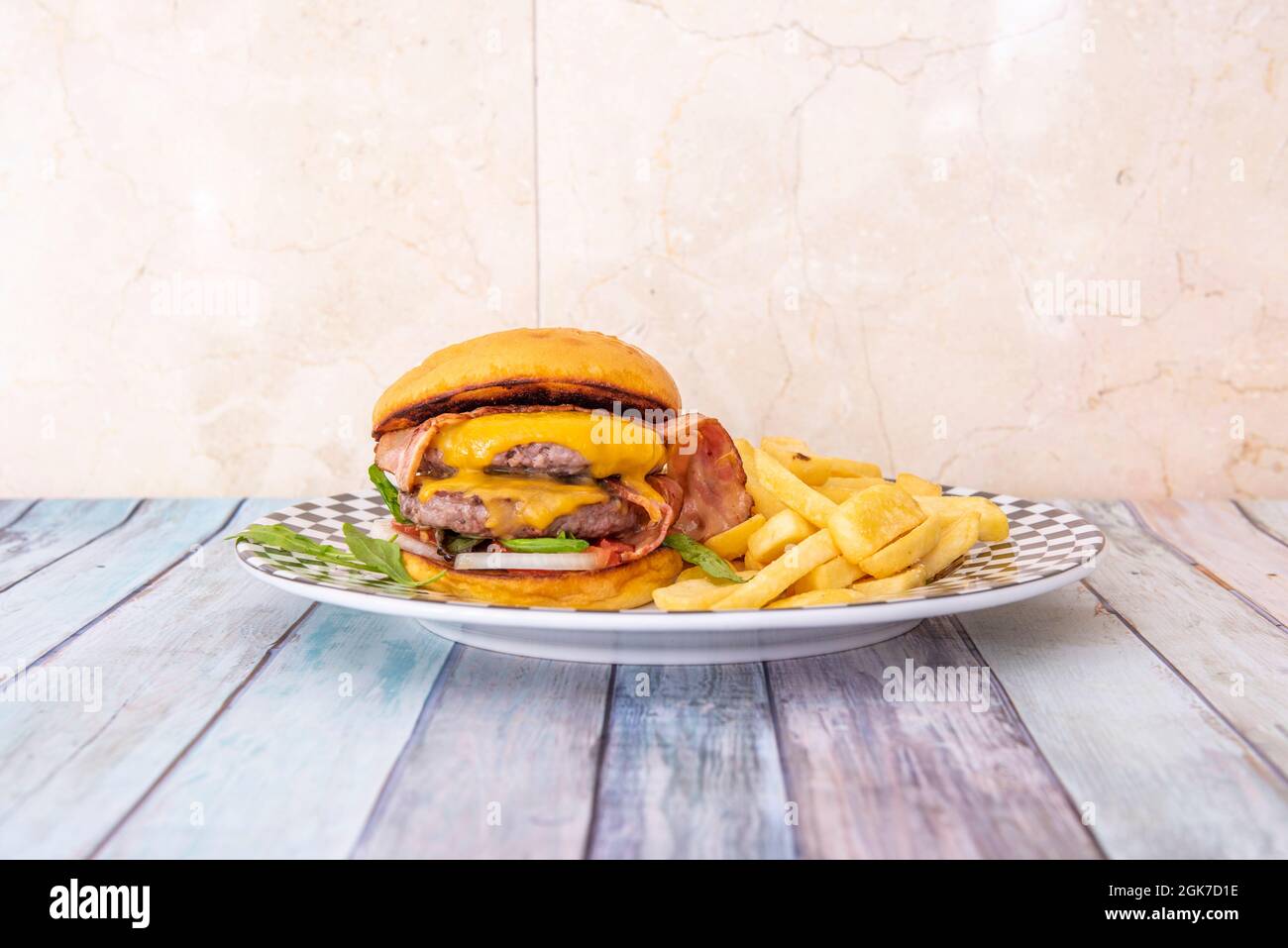Beef burger with double meat, melted cheddar cheese and slices of fried bacon and white onion Stock Photo