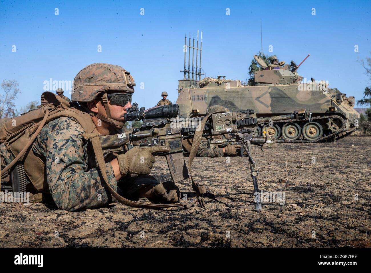 U.S. Marine Corps Lance Cpl. Yorvi Colladopichardo, a rifleman with Company B., 1st Battalion, 7th Marine Regiment (Reinforced), Marine Rotational Force – Darwin, lies in a prone position next to an Australian M113 AS4 Armored Personnel Carrier during a dry-run rehearsal at Bradshaw Field Training Area, NT, Australia, Aug. 25, 2021. The dry-run rehearsals were in preparation for a live-fire event between Marines and the Australian Army for Exercise Koolendong. Exercise Koolendong validates MRF-D’s and the Australian Defence Force’s ability to conduct expeditionary command and control operation Stock Photo