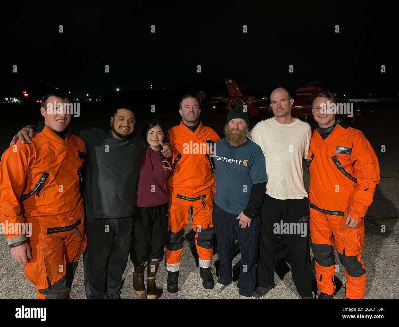 A Coast Guard MH-65 Dolphin helicopter crew from Air Station Kodiak deployed aboard Cutter Bertholf shares a moment with four survivors in Dutch Harbor after hoisting them from a rock near the grounded fishing vessel Endurance, about one mile west of Egg Island, near the entrance to Beaver Inlet, Unalaska, August 26, 2021. The survivors were then placed in the care of awaiting EMS in Dutch Harbor with no injuries reported at the time of transfer. Stock Photo