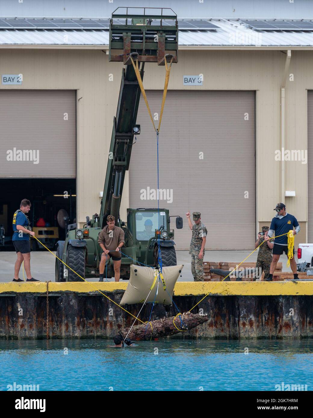 210826-N-OT701-1278 KANEOHE BAY, Hawaii Aug. 26, 2021 -- Sailors assigned to Mobile Diving and Salvage Unit ONE Detachment Explosive Ordnance Disposal Group (MDSU ONE DET EOD) lift an unexploded ordnance Stock Photo