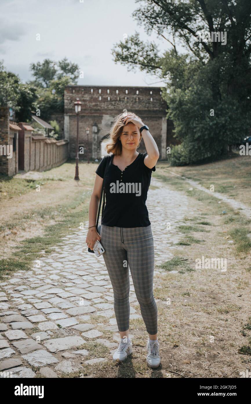 Vertical of a beautiful Bosnian female posing on the pathway against the castle Stock Photo