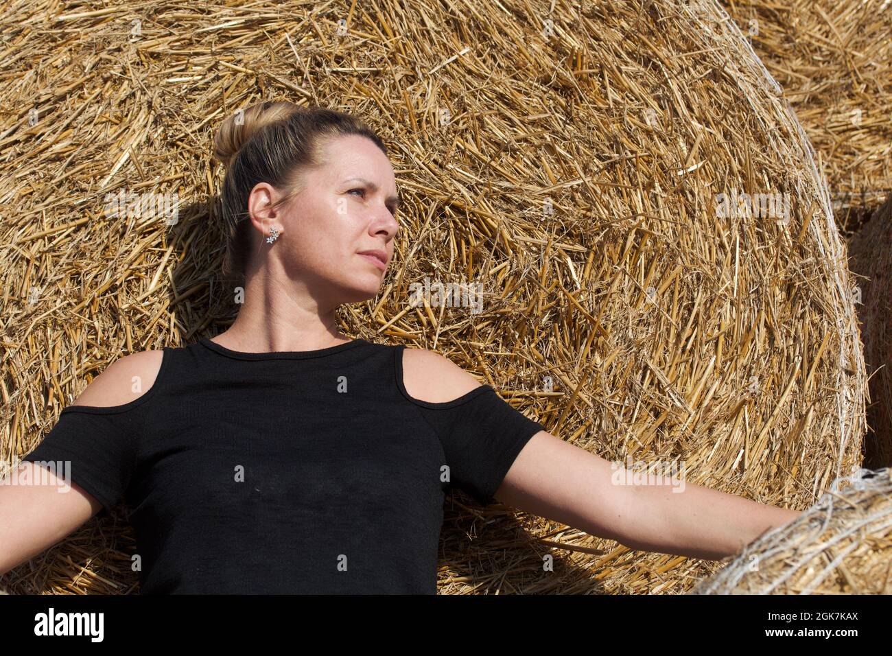 Girl posing near a stack of straw. Straw rolls, stacked in a pyramid ...