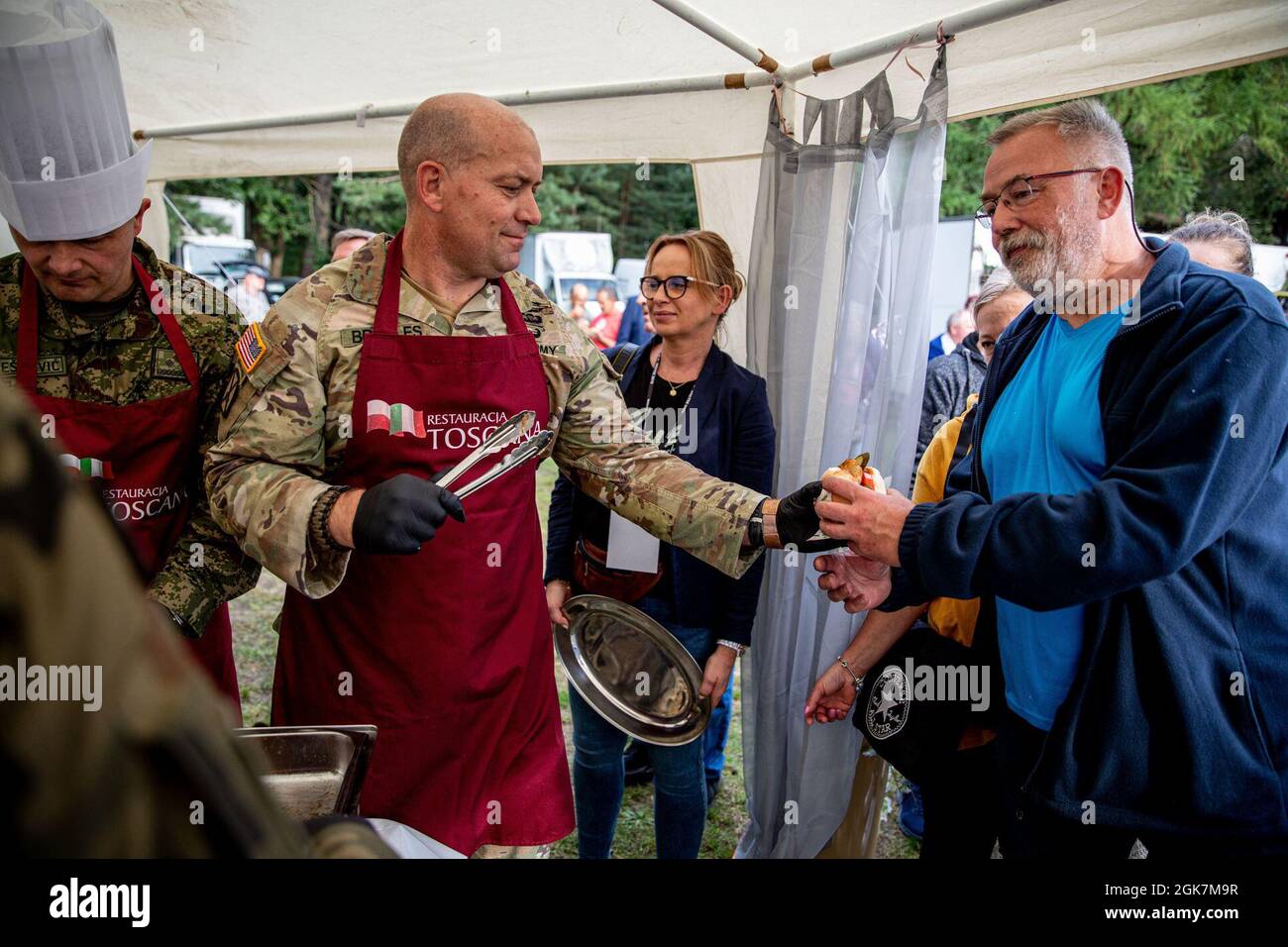 U.S. Army Lt. Col. Craig Broyles, commander of Battle Group Poland, hands a fish burger to a local citizen during the Days of Orzsyz festival in Orzysz, Poland, August 27, 2021. Battle Group Poland's leaders joined the local community to celebrate the Days of Orzysz, strengthening our partnership. Stock Photo