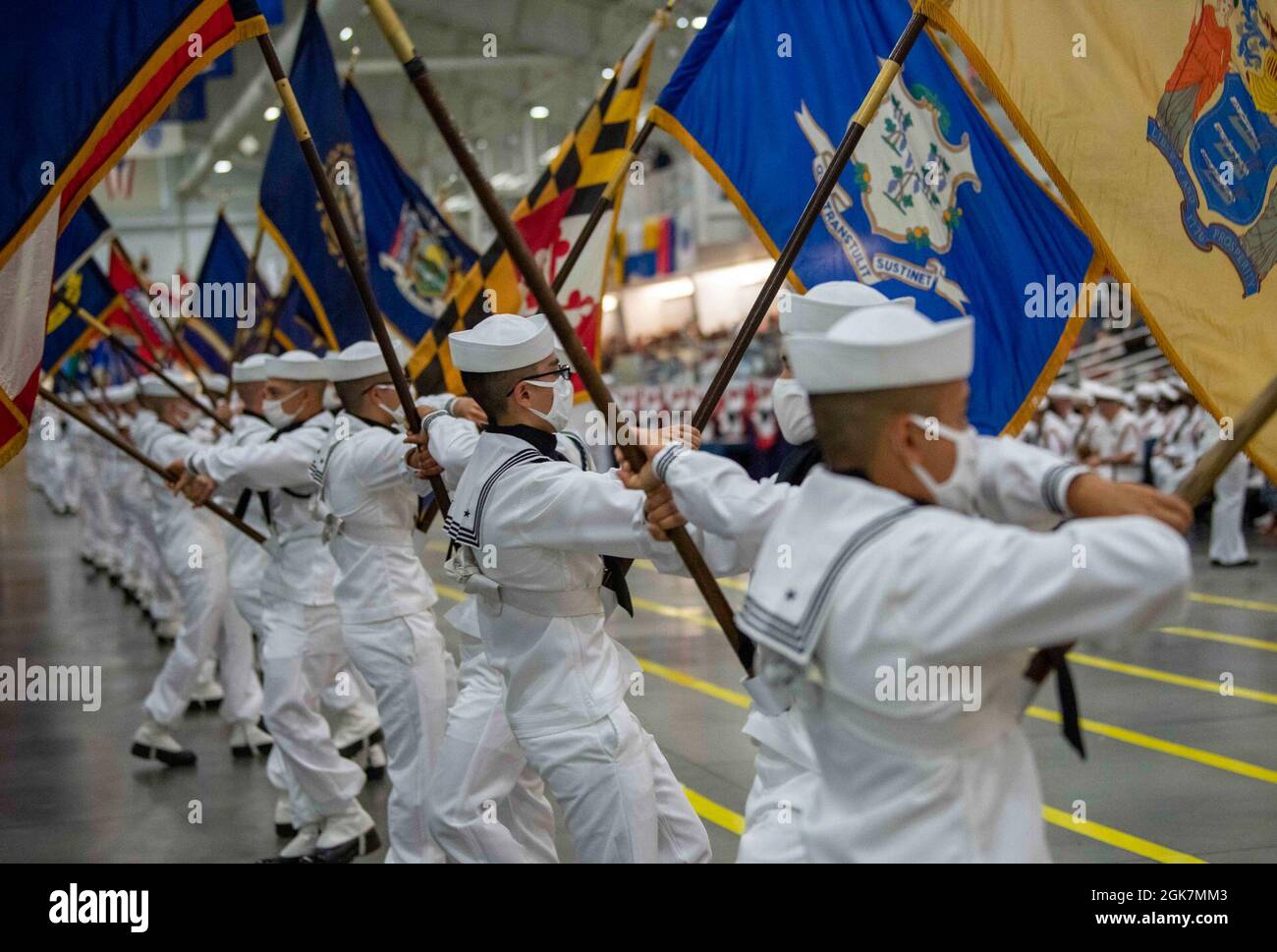 Performance division recruits carrying state flags march on the drill deck during a pass-in-review graduation ceremony at Recruit Training Command. More than 40,000 recruits train annually at the Navy's only boot camp. Stock Photo