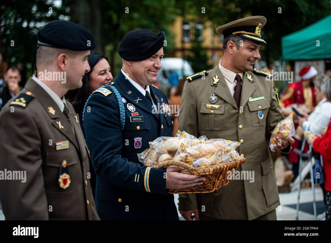 From left, Croatian Land Forces Capt. Dario Biljeskovic, commander of Storm Battery, U.S. Army Lt. Col. Craig Broyles, commander of Battle Group Poland, and Romanian Land Forces Maj. Mircea Zemtev, commander of Sky Guardians, hand out bread to Orzysz citizens during the Harvest Festival in Orzysz, Poland, August 29, 2021. Battle Group Poland's leaders joined the local community to celebrate the Days of Orzysz and the Harvest Festival, strengthening our partnership. Stock Photo