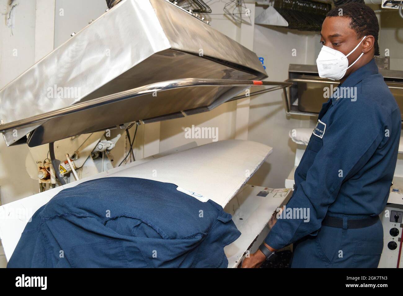 210828-N-UP745-1221 ATLANTIC OCEAN (Aug. 28, 2021) Retail Services Specialist 3rd Class Cortez West, from Tampa Bay, Florida, flat presses a coverall aboard the USS Forrest Sherman (DDG 98). USS Forrest Sherman (DDG 98) participates in FRONTIER SENTINEL alongside U.S. Coast Guard, and Canadian Allies to enhance their Arctic capabilities Stock Photo