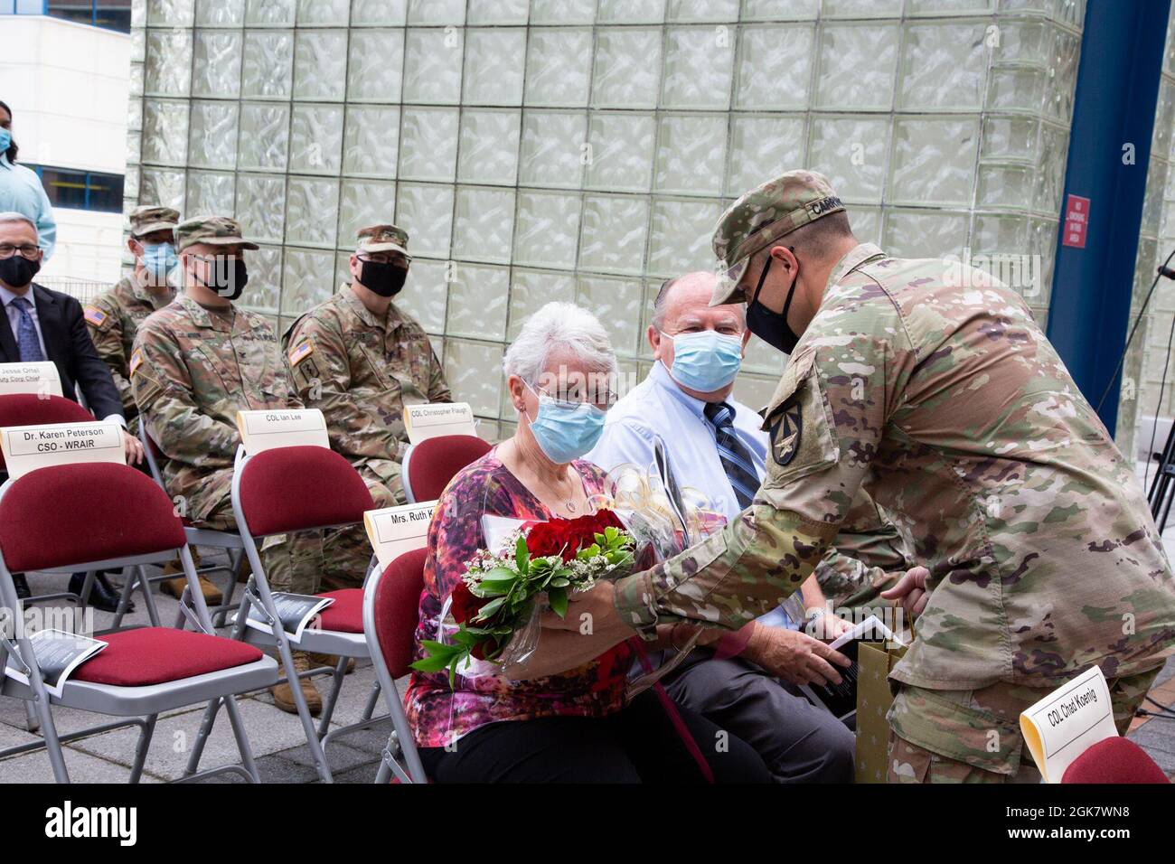 Sgt. Dalton Carrington presents flowers to Ruth Koenig during an assumption of command ceremony, August 31, 2021, Silver Spring, Md. Col. Chad Koenig assumed command of the Walter Reed Army Institute of Research during the ceremony and thanked his parents for years of support. Stock Photo