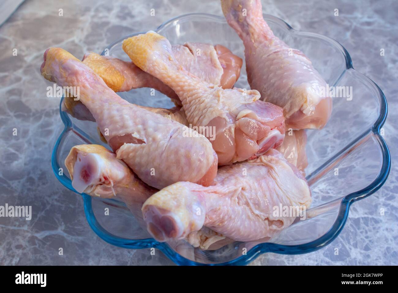 Closeup raw chicken legs in glass bowl. Uncooked chicken drumsticks