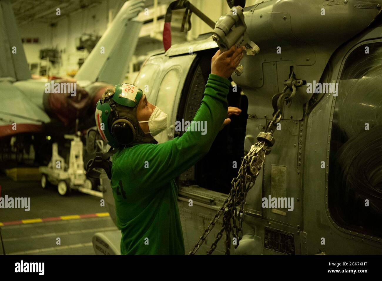 210831-N-MD461-1089 PACIFIC OCEAN (August 31, 2021) Aviation Machinist’s Mate 1st Class Kenneth Rey Chua, a native of Cavite, Philippines, assigned to the “Black Knights” of Helicopter Sea Combat Squadron (HSC) 4, conducts maintenance on an MH-60S Seahawk in the hangar bay aboard Nimitz-class aircraft carrier USS Carl Vinson (CVN 70), August 31, 2021. Carl Vinson Carrier Strike Group is on a scheduled deployment in the U.S. 7th Fleet area of operation to enhance interoperability with allies and partners to serve as a ready-response force in support of a free and open Indo-Pacific region. Stock Photo