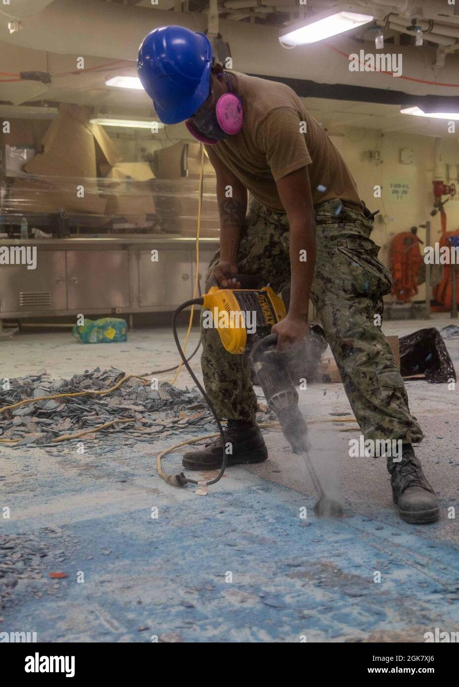 Aviation Boatswain's Mate (Handling) Airman Justin Miller, from Miami, assigned to USS Gerald R. Ford's (CVN 78) air department, removes PRORECO deck coating (PRC) in Ford’s aft galley, Aug. 31, 2021. PRC is a marine deck-coating made of a resin sealer and color epoxy that is designed to resist heavy abrasion, impact and other potential movements. Ford is moored at Newport News Shipyard in support of her Planned Incremental Availability (PIA), a six-month period of modernization, maintenance and repairs. Stock Photo