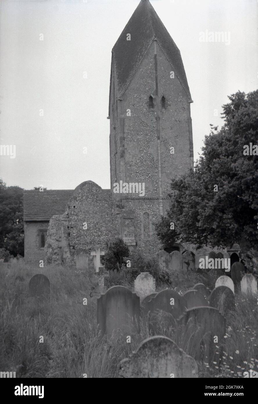 1962, historical, view from this era of the distinctive church tower of St Mary's with its Rhenish helm, at Sompting, Littelhampton, West Sussex, England, UK and surrounding graveyard. The four-sided pyramid-style gabled cap on top of the saxon tower is an unusual feature in England. The flint built church was of such exceptional historical importance, that it was listed as a Grade I building by English Heritage in 1954, making it a rare building as only 2.5% of all listed buildings in England are classified as Grade 1. Stock Photo