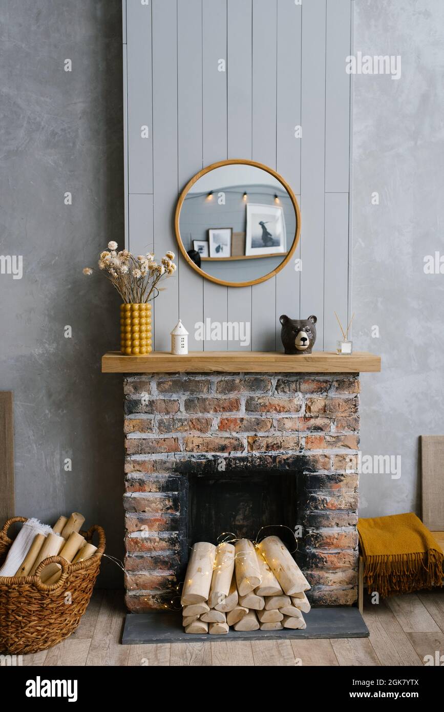 Stylish Scandinavian minimalist interior with a brick fireplace and wood fire. Cozy house. The modern interior of the country house is decorated in gr Stock Photo