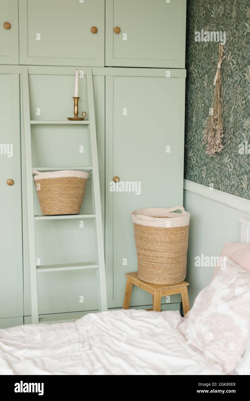 The interior of the bedroom is in the Scandinavian style. Mint cupboard by  the bed and laundry baskets Stock Photo - Alamy