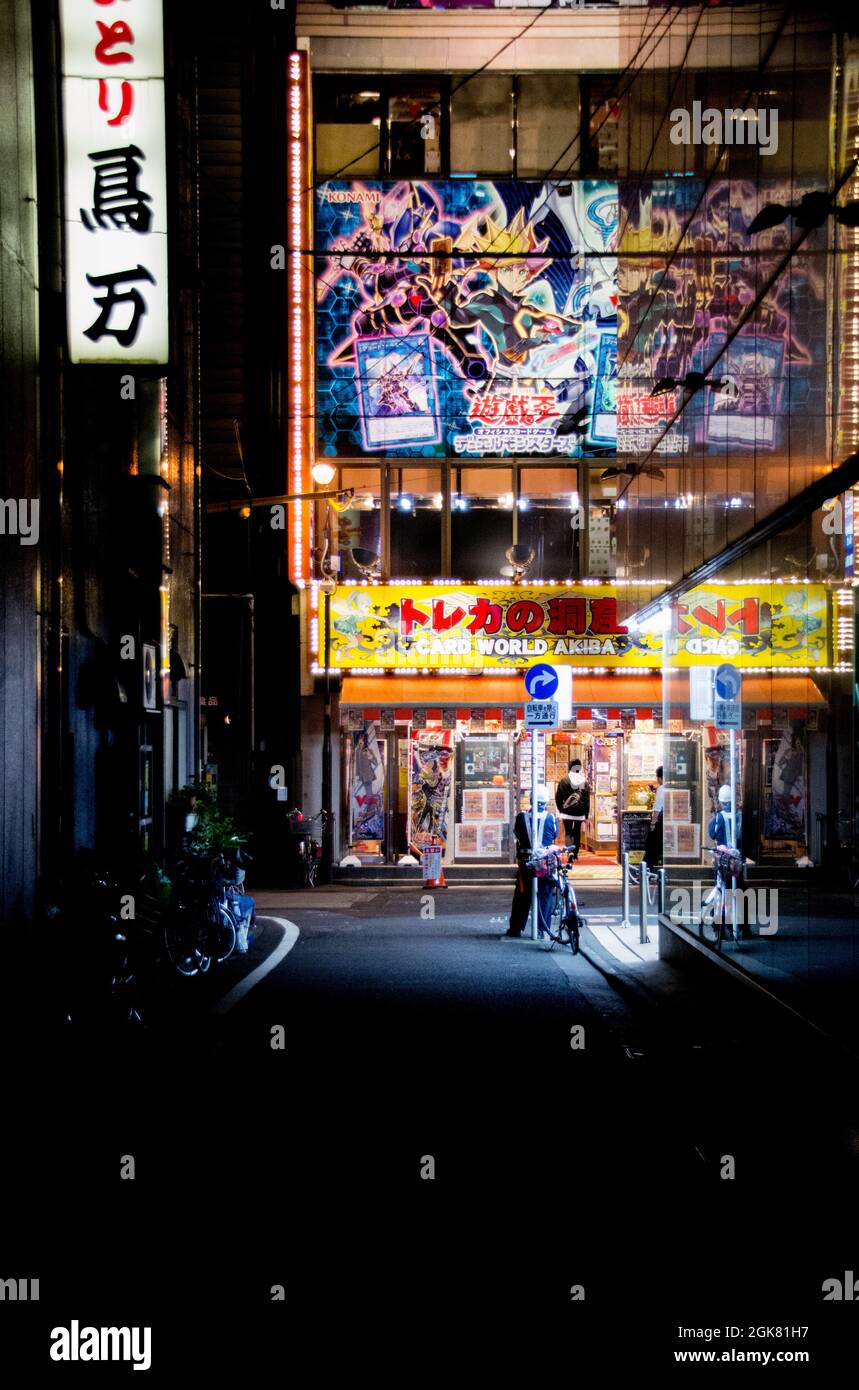 A pedestrian standing looking up at the neon lights in a sidestreet in Akihabara, Tokyo, Japan, October Stock Photo