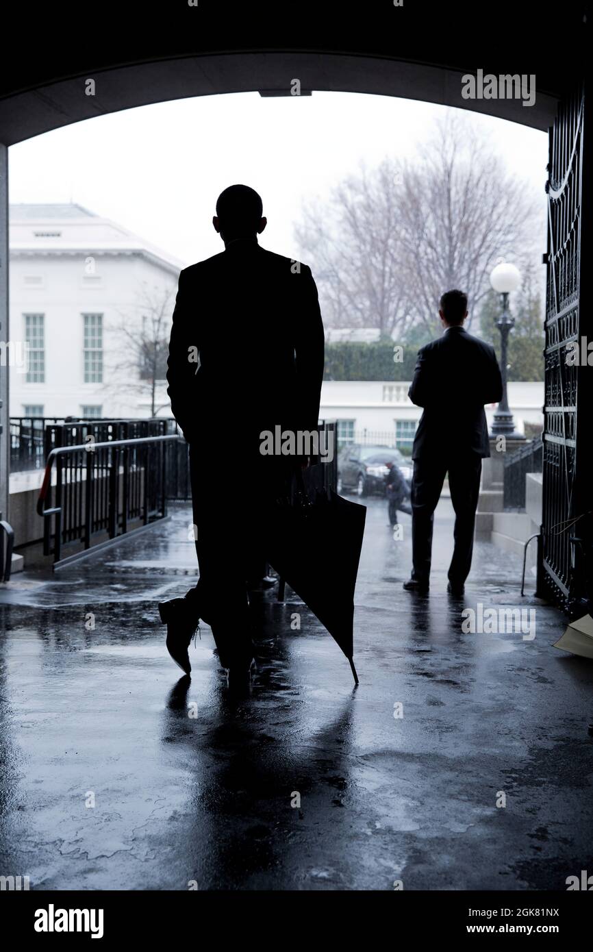 President Barack Obama waits for a heavy rain to pass before crossing West Executive Avenue from the Eisenhower Executive Office Building to the West Wing of the White House, March 12, 2013. (Official White House Photo by Pete Souza) This official White House photograph is being made available only for publication by news organizations and/or for personal use printing by the subject(s) of the photograph. The photograph may not be manipulated in any way and may not be used in commercial or political materials, advertisements, emails, products, promotions that in any way suggests approval or end Stock Photo