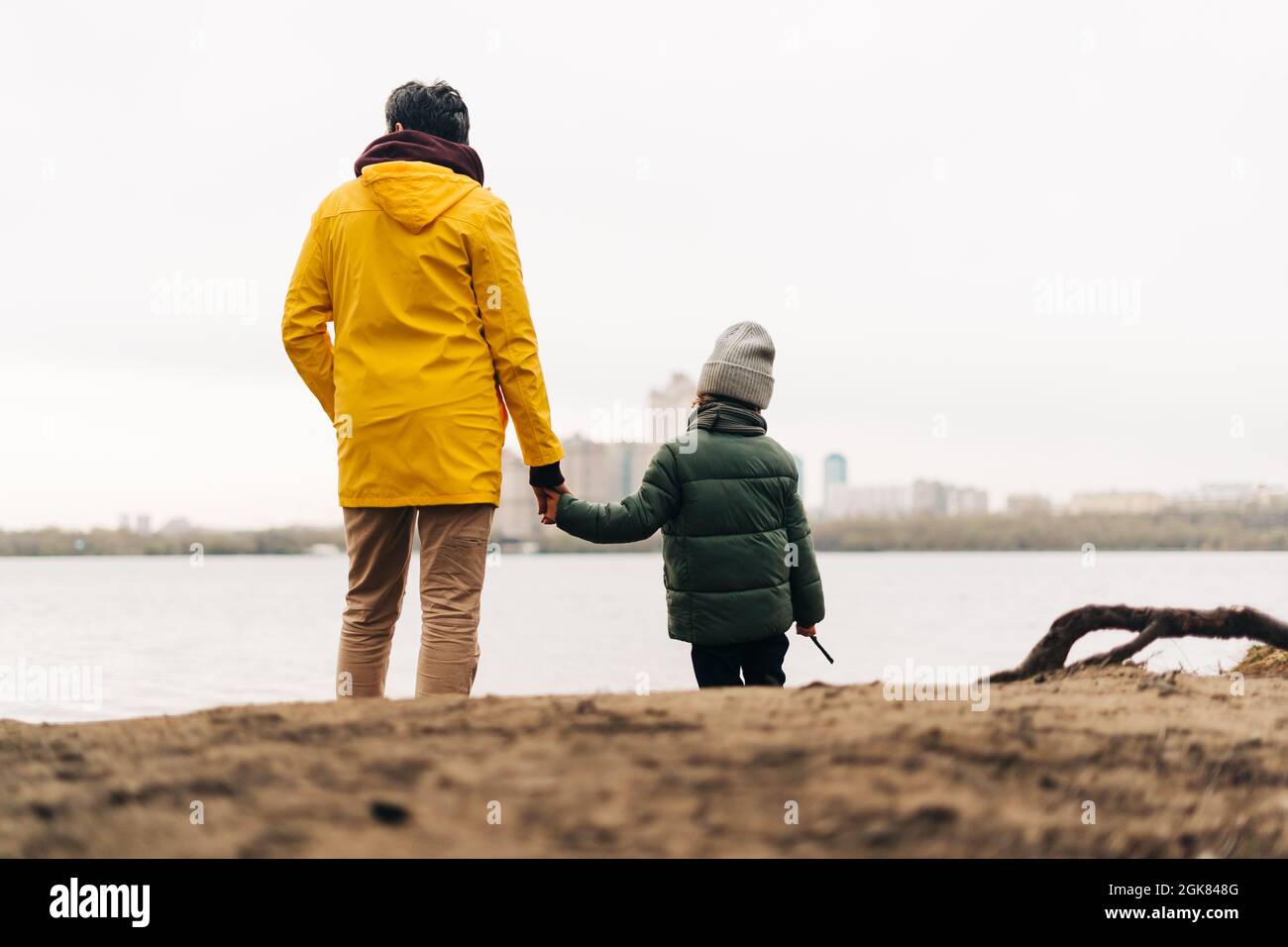 Father and son stand on the shore of the lake and hold hands. Happy family with child kid boy playing and having fun outdoors over autumn park Stock Photo