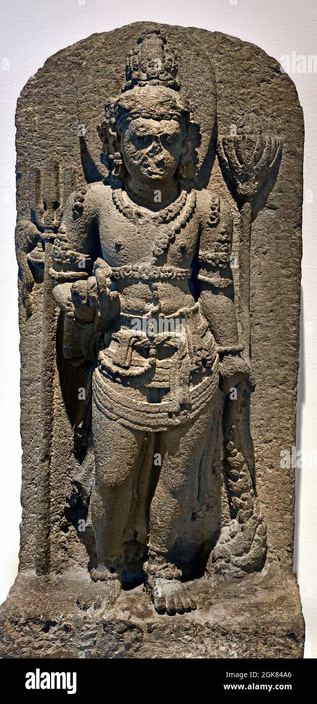 Nandishvara, 800-900, volcanic rock  76.5cm × 37cm × 22cm Indonesia, Central Java, Nandishvara is one of the two guardians, Temple of the Hindu god Shiva. He has the appearance of a cultured young man and stands on Shiva's right side, In one hand he has a necklace with prayer beads, in his other hand hangs a floating lotus flower. The trident is Shiva's weapon. Indonesia, Stock Photo