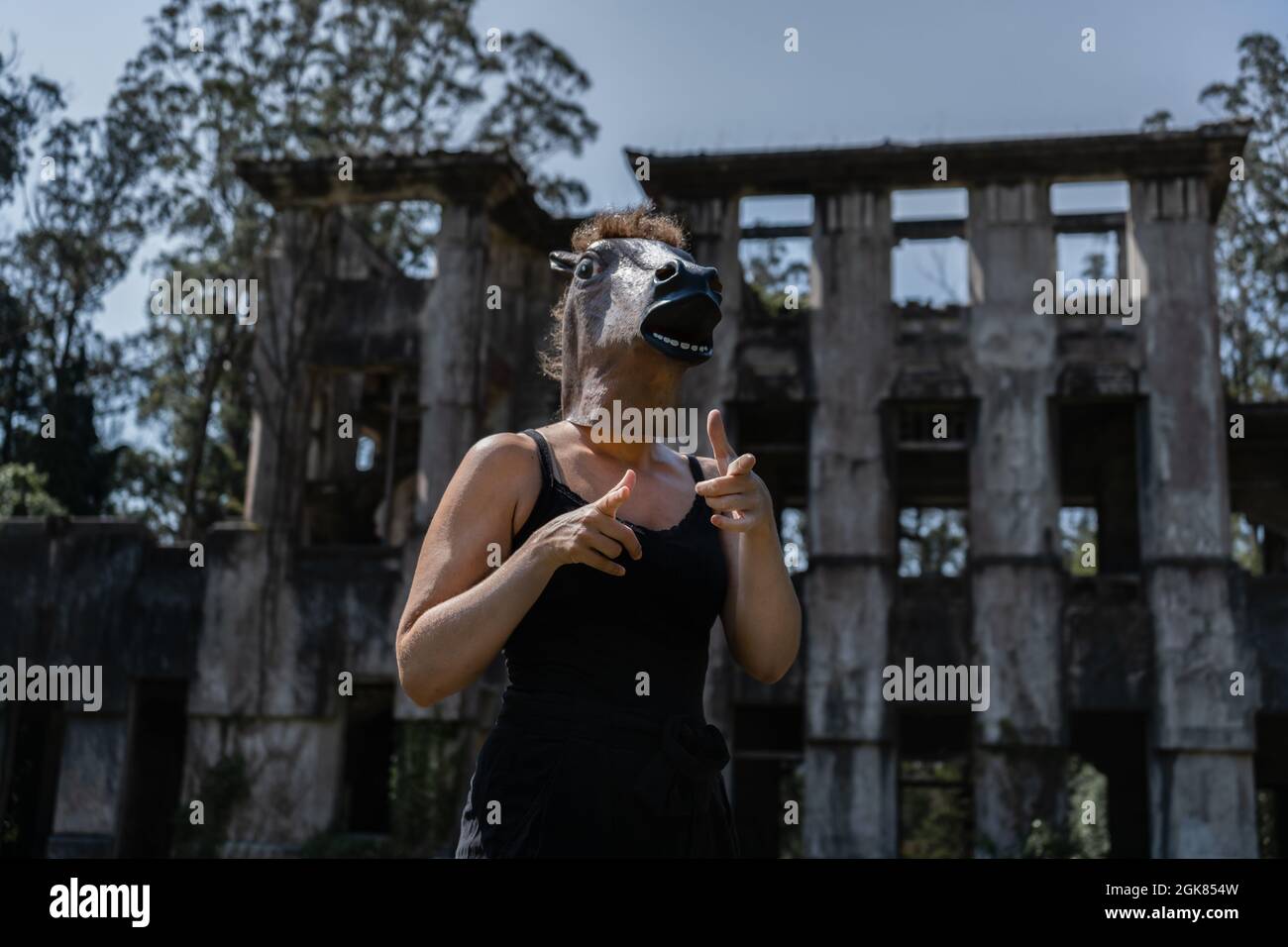 Female in horse mask pointing at camera against old ruins house Stock Photo