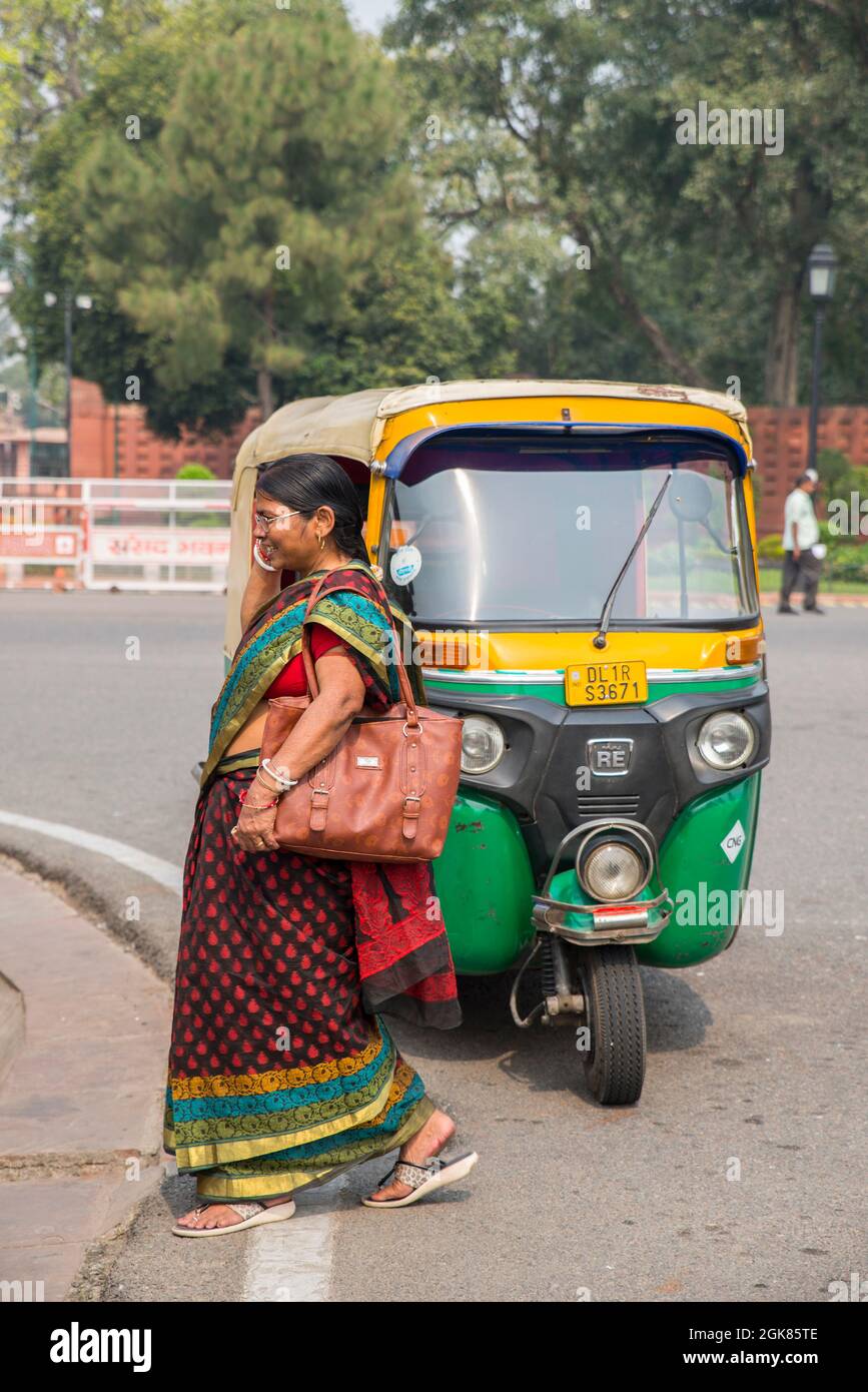 Woman walking in front of Tuk Tuk in New Delhi, India Stock Photo