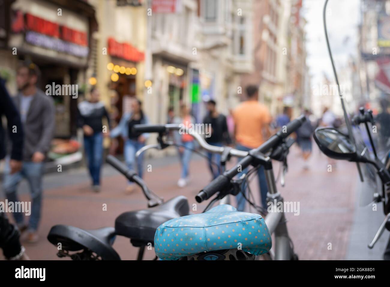 Blue bicycle seat in focus with surrounding city street scene and ...