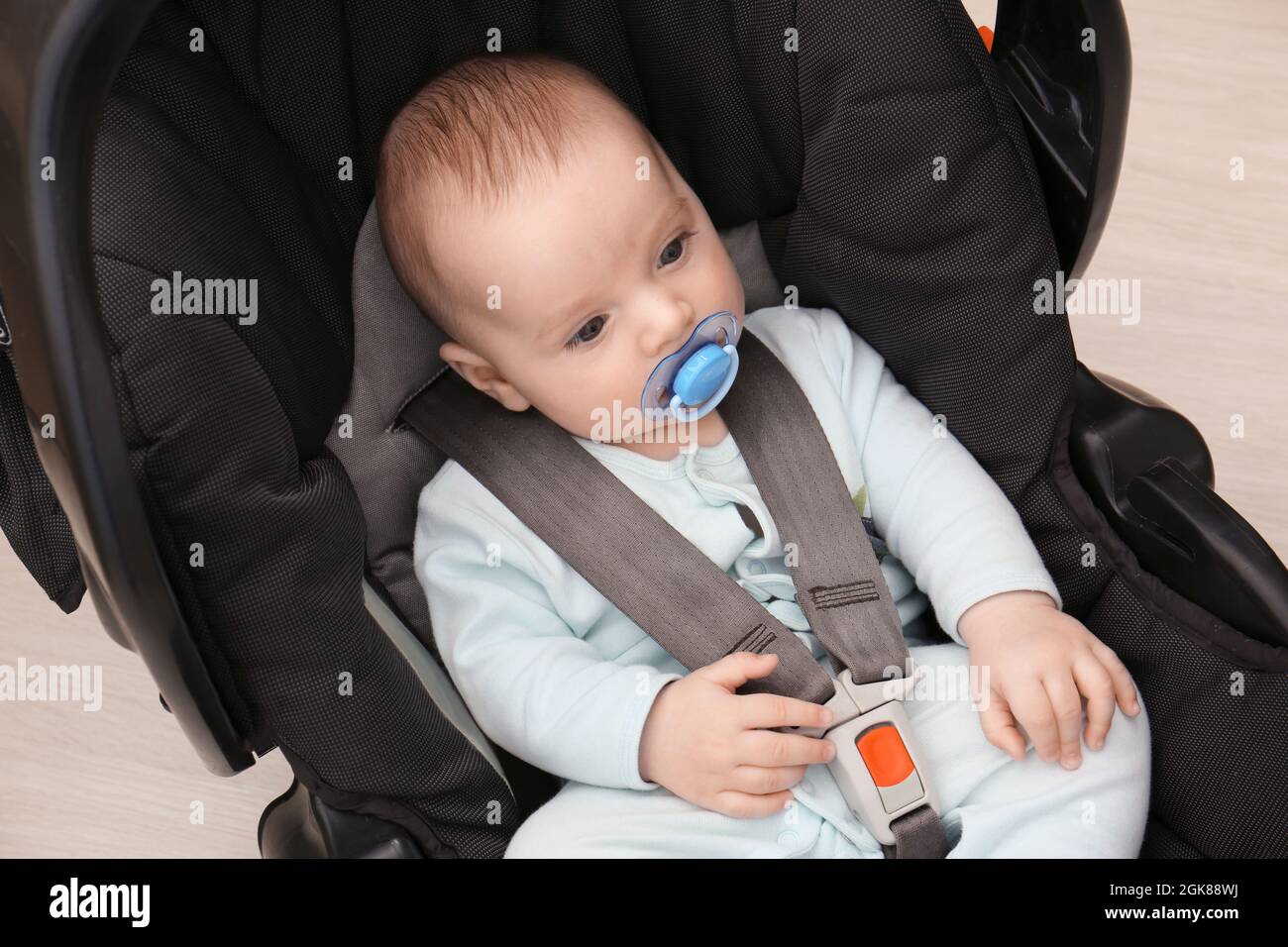 Cute baby boy with pacifier sitting in safety car seat Stock Photo Alamy