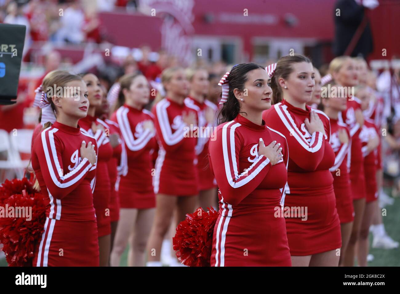 BLOOMINGTON, UNITED STATES - 2021/09/11: Indiana University cheerleaders place their hands over their hearts during the playing of the national anthem on the anniversary of the 9/11 attack before Indiana University's plays against Idaho during an NCAA football game on September 11, 2021 at Memorial Stadium in Bloomington, Ind. The Hoosiers beat the Vandals 56-14. Stock Photo