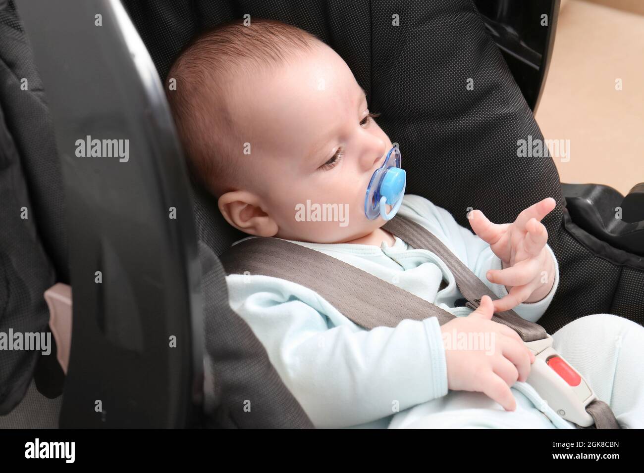 Cute baby boy with pacifier sitting in safety car seat Stock Photo Alamy