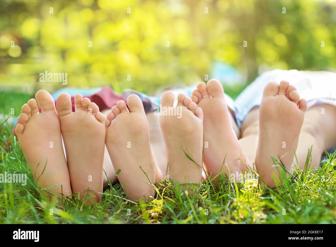 Feet of cute little children lying on green grass in park Stock Photo ...