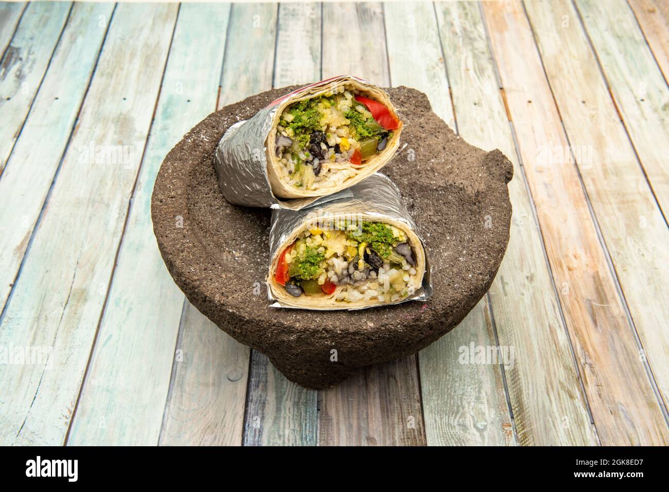 https://c8.alamy.com/comp/2GK8ED7/large-burrito-halved-wrapped-in-aluminum-foil-stuffed-with-green-chorizo-black-beans-and-rice-with-cheese-on-volcanic-stone-molcajete-2GK8ED7.jpg