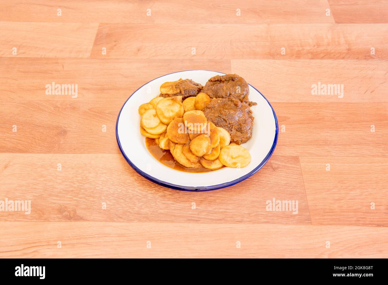 fantastic portion of pork cheeks in sauce garnished with french fries and on a white enameled plate Stock Photo