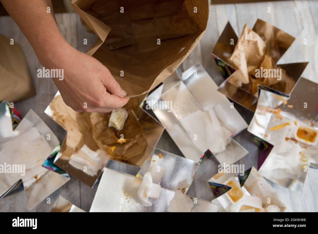 Female hands are wrapping paper bags from delivered food. Waste paper
