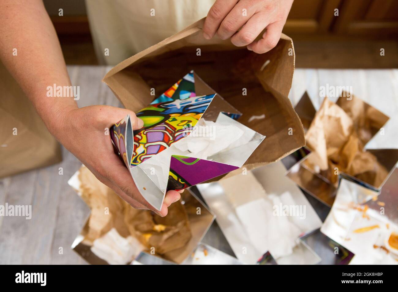 Female hands are wrapping paper bags from delivered food. Waste paper