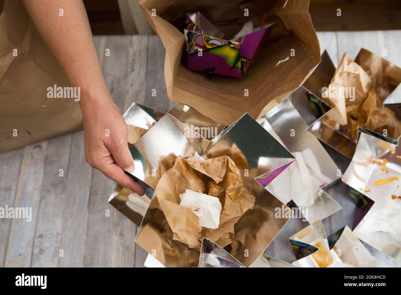 Female hands are wrapping paper bags from delivered food. Waste paper is placed in separate paper waste bins for recycling. Stock Photo