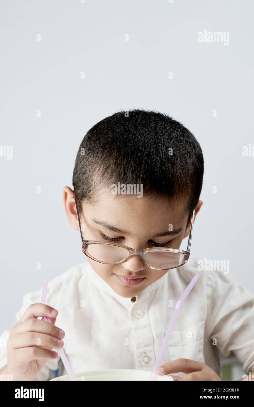 A little nerd kid in big glasses busy with chemical experiments against