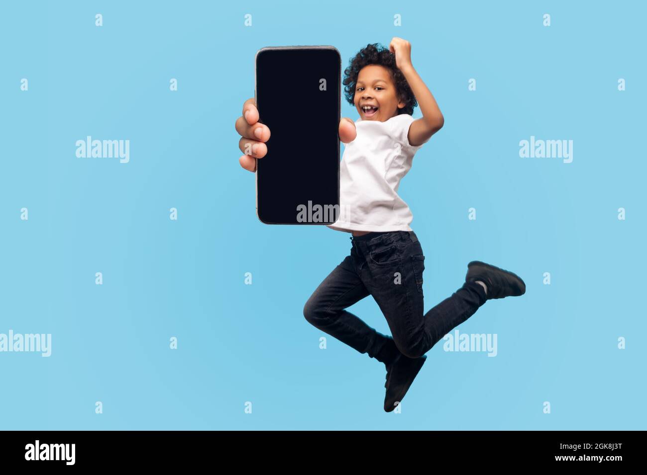 Full length, lively energetic little boy jumping with happiness and