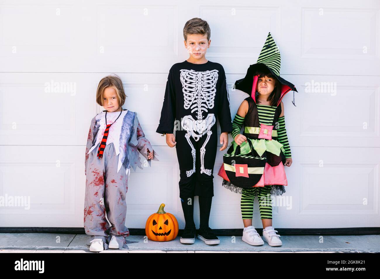 Full body of group of little kids dressed in various Halloween costumes  with carved Jack O Lantern standing near white wall on street Stock Photo -  Alamy