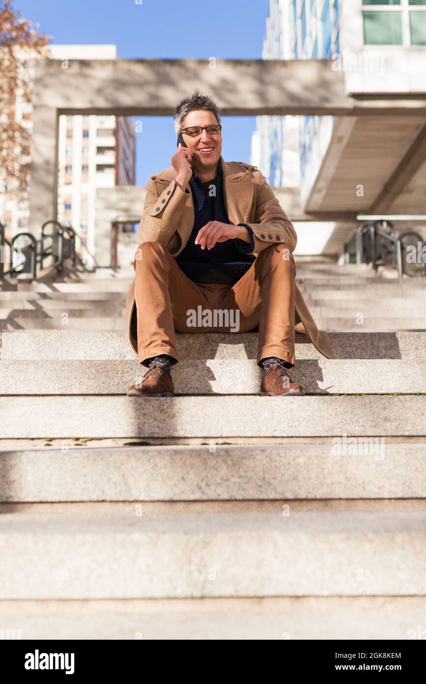 Stylish young man in glasses and casual clothes sitting on stairs Stock ...