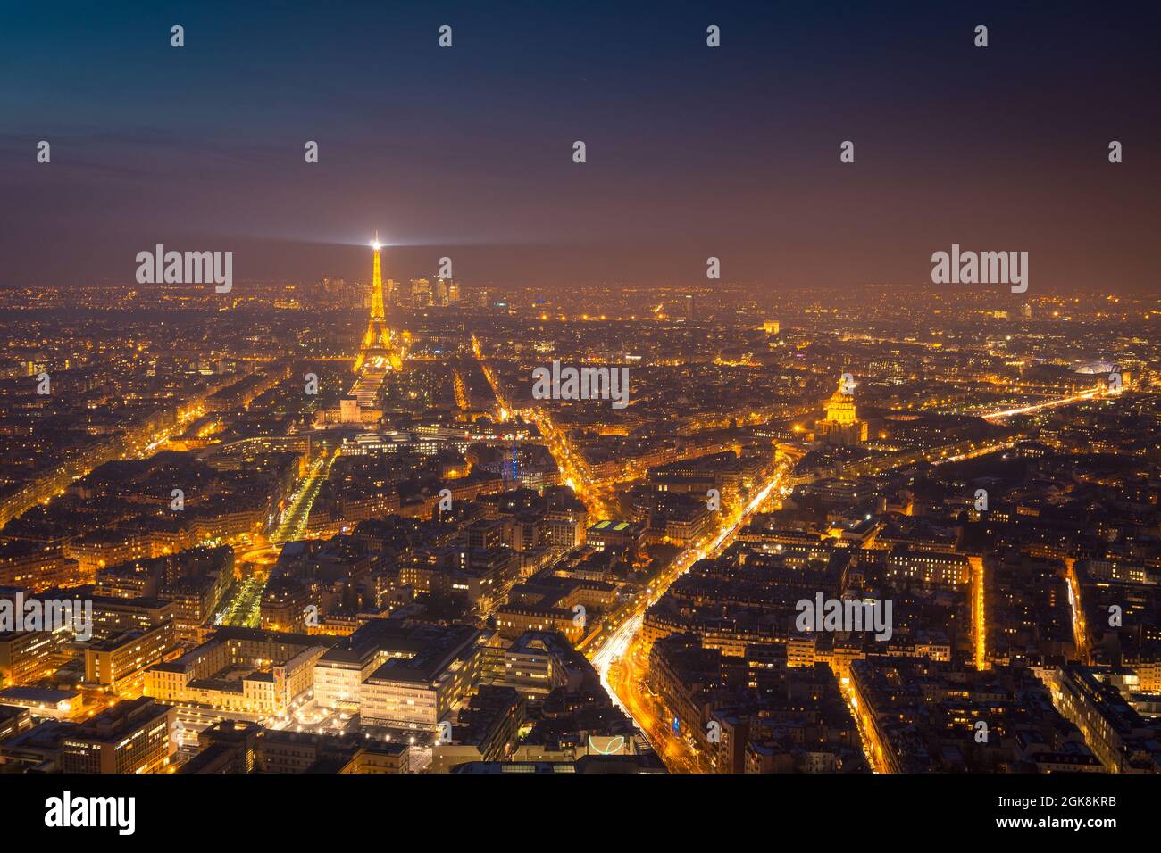 Aerial view of dark night sky above illuminated buildings and roads with high Eiffel Tower in district of Paris Stock Photo