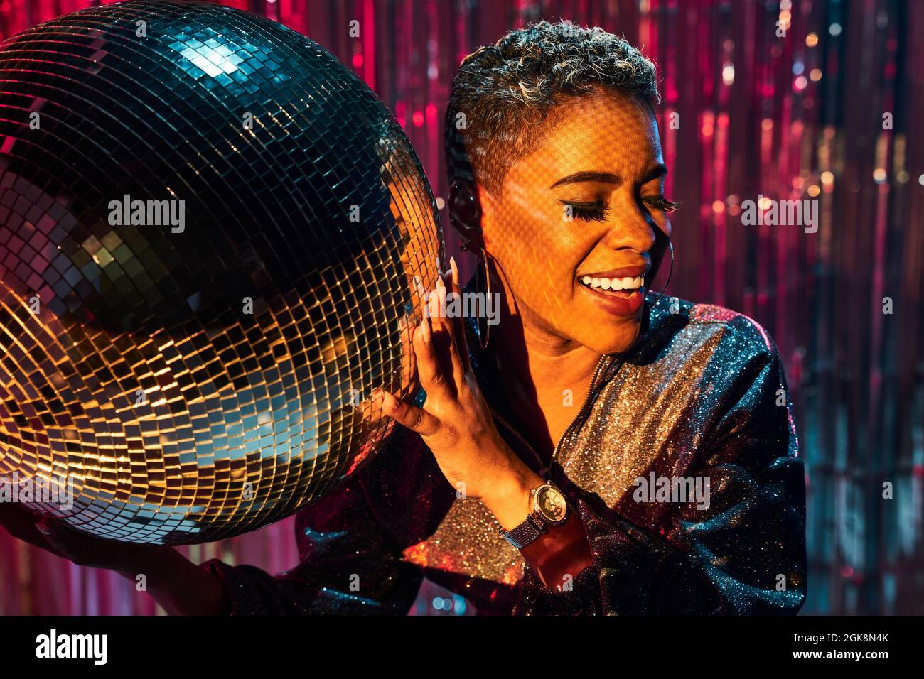 Trendy young cheerful ethnic female with eyes closed holding mirror