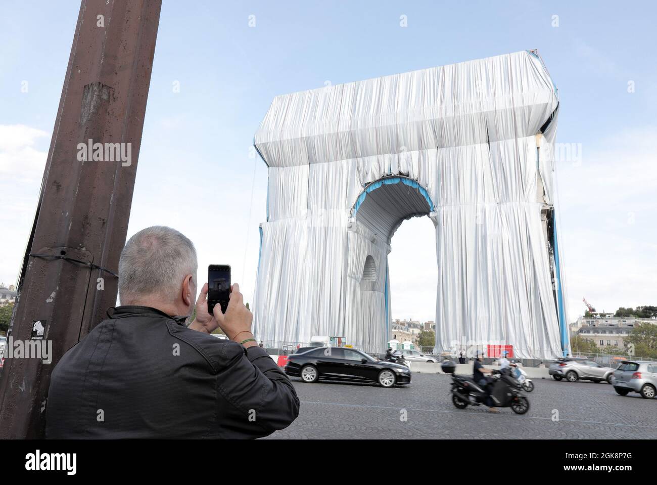 Paris, France. 13th Sep, 2021. A man takes a snapshot of the Arc de Triomphe as it is being wrapped in silvery blue fabric in Paris, France, on Monday, September 30, 2021. The landmark is covered with 25,000 square meters of material, posthumously fulfilling a 60-year dream for the artist Christo. Photo by Eco Clement/UPI Credit: UPI/Alamy Live News Stock Photo