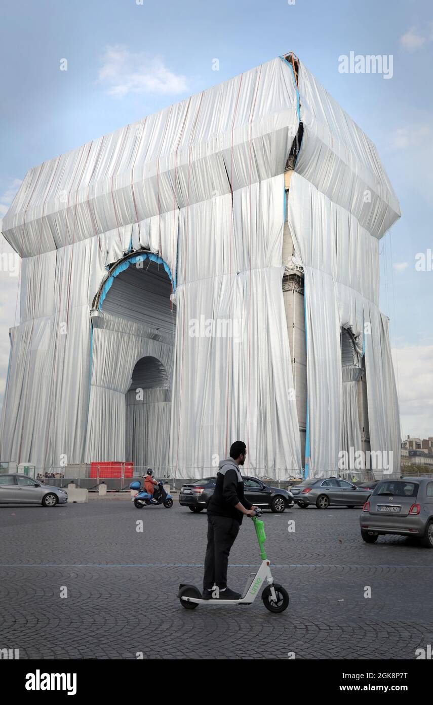 Paris, France. 13th Sep, 2021. An electric scooter drives past the Arc de Triomphe as it is being wrapped in silvery blue fabric in Paris, France, on Monday, September 30, 2021. The landmark is covered with 25,000 square meters of material, posthumously fulfilling a 60-year dream for the artist Christo. Photo by Eco Clement/UPI Credit: UPI/Alamy Live News Stock Photo