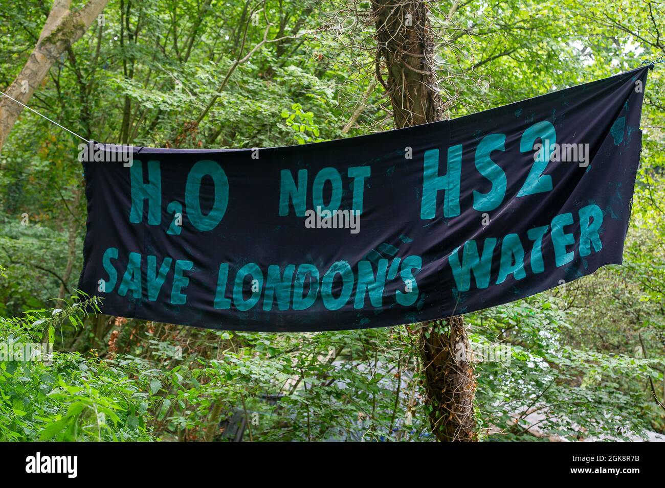 Denham, Buckinghamshire, UK. 13th September, 2021. An H2O not HS2, Save London's Water banner at the Denham Ford Protection Camp in Denham Country Park. Legal action has begun against the Environment Agency about the impact HS2 tunnelling through the Chilterns will have upon the chalk streams. The High Speed Rail link from London to Birmingham puts 693 wildlife sites, 108 ancient woodlands and 33 SSSIs at risk. Credit: Maureen McLean/Alamy Stock Photo