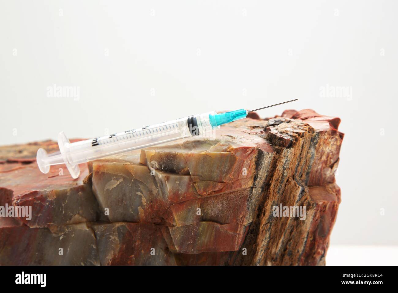 Injection needle on rock reflects solid public health recommendations with firm data to support vaccine guidance in conceptual image Stock Photo